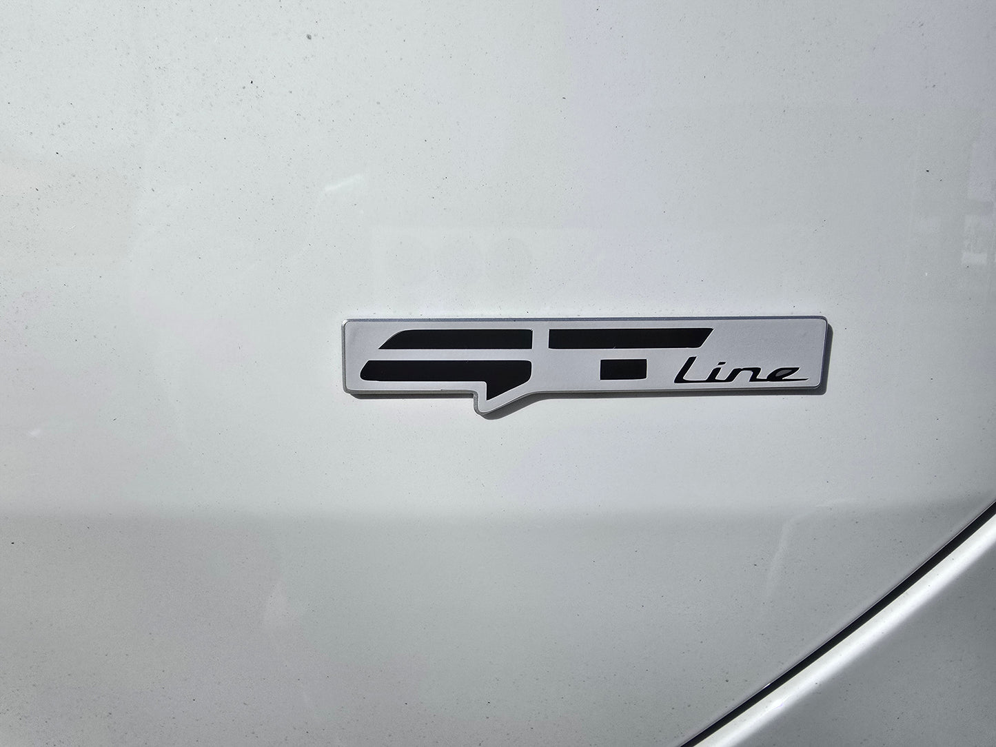 Car badge with 'GT Line' text on a silver car surface