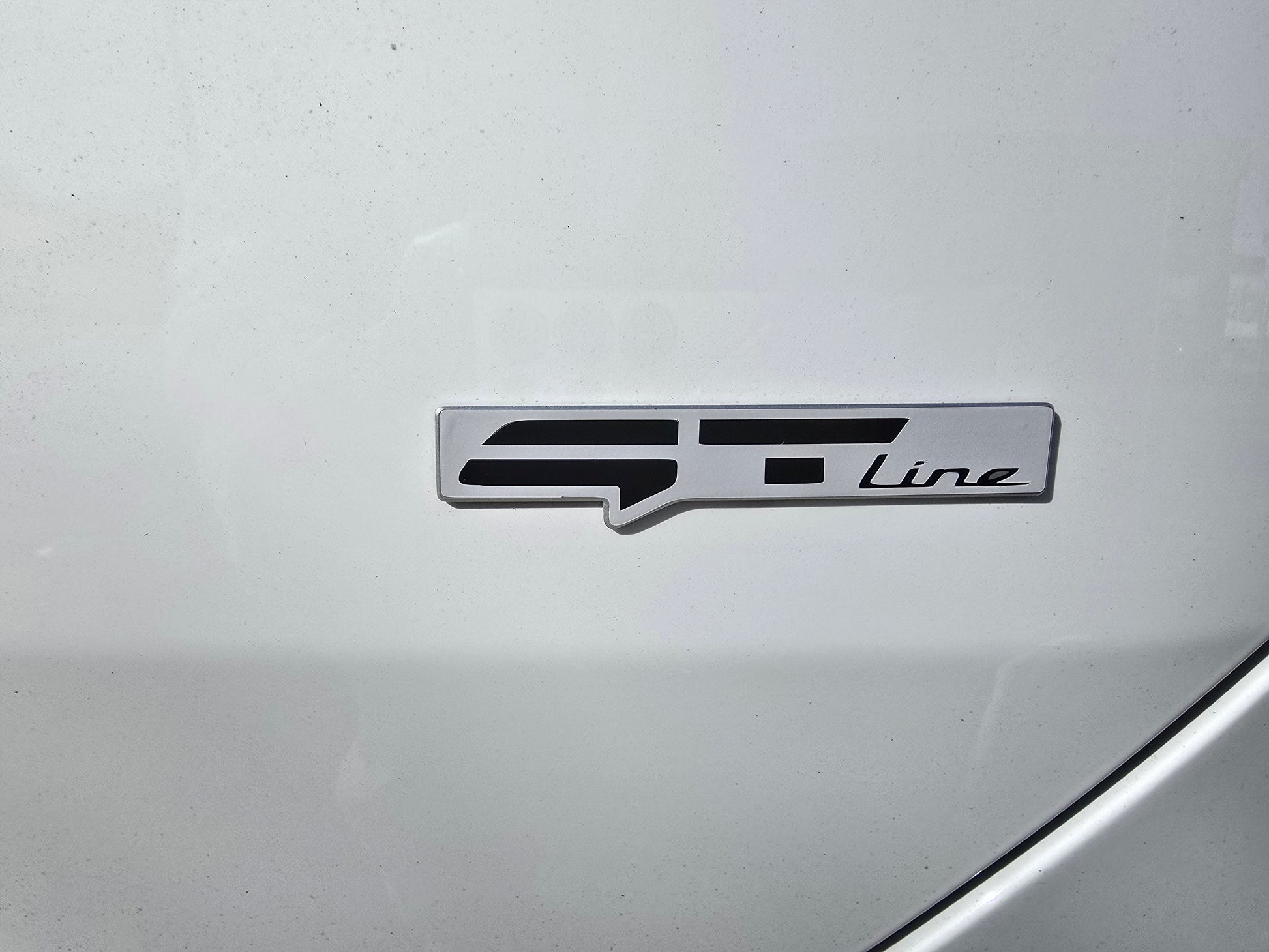 Car badge with 'GT Line' text on a silver car surface